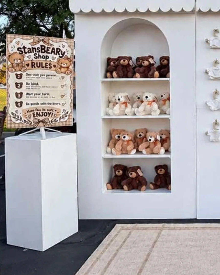 Arched white shelves of teddy bears beside a rules sign at the Stans BEARy Shop