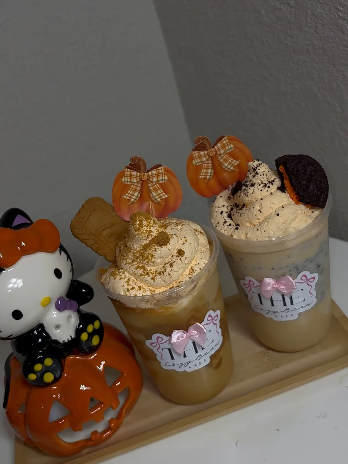 Two fall lattes with orange whipped cream, a cookie, and pumpkin picks