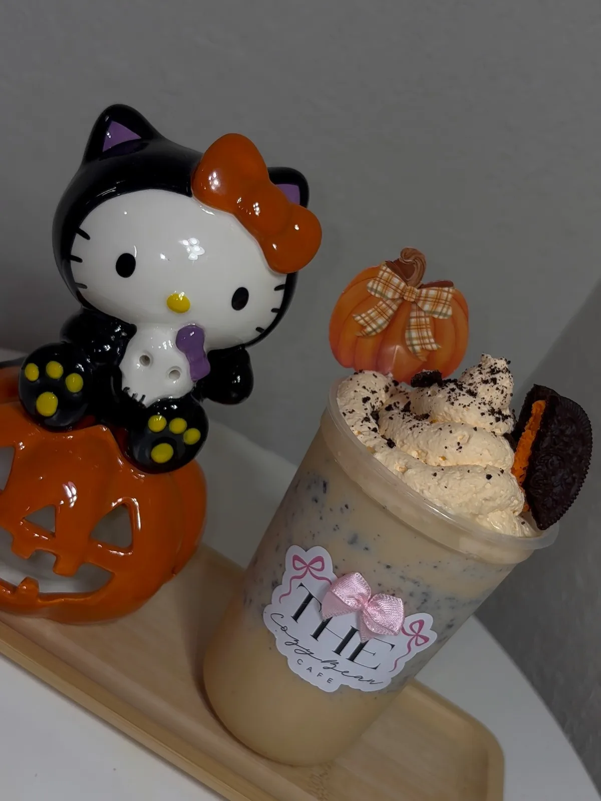 A cookies-and-cream latte topped with orange whipped cream, an Oreo, and a pumpkin pick
