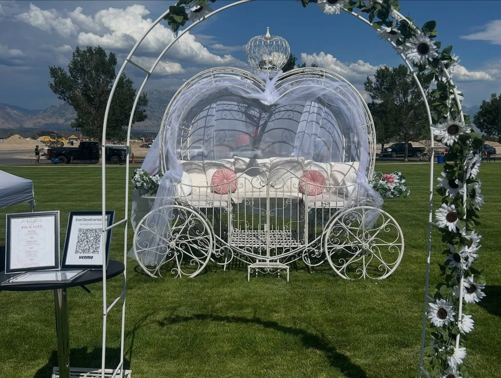 The EverGlow Events white heart-shaped Cinderella carriage framed by a flowered arch
