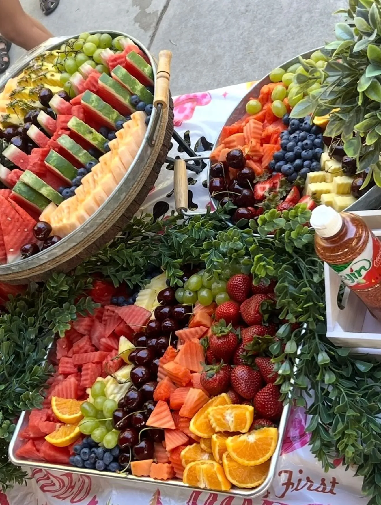 A fruit table with watermelon, mango, strawberries, and cherries