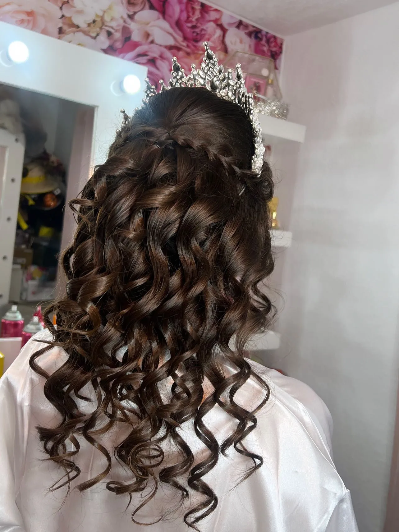 Long curls and a half-up braid beneath a silver tiara