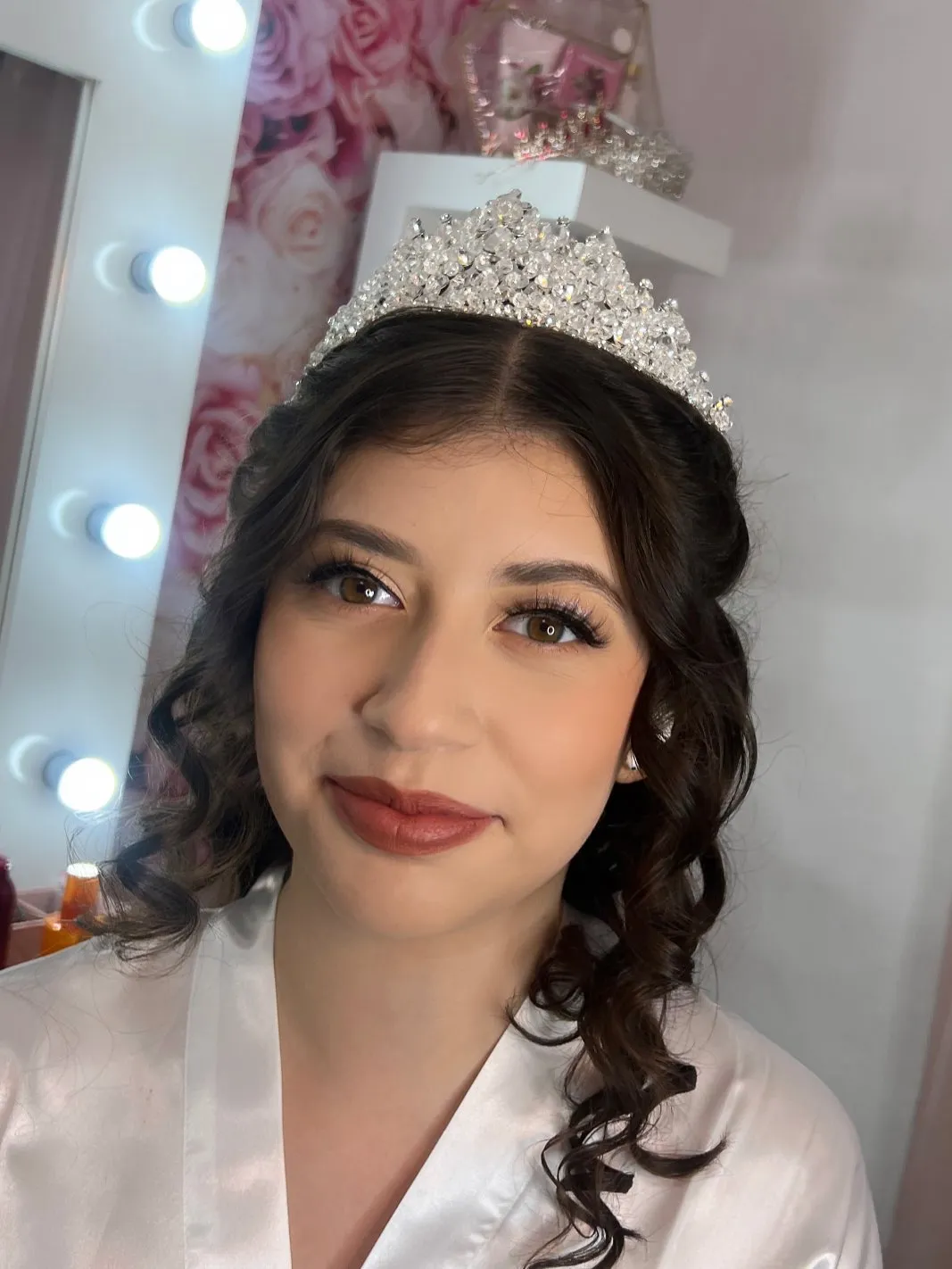 A quinceañera in a crystal tiara with soft makeup and curls
