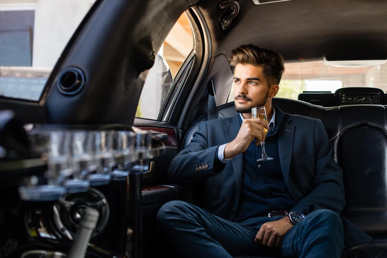 A guest relaxing inside a limousine with a glass in hand