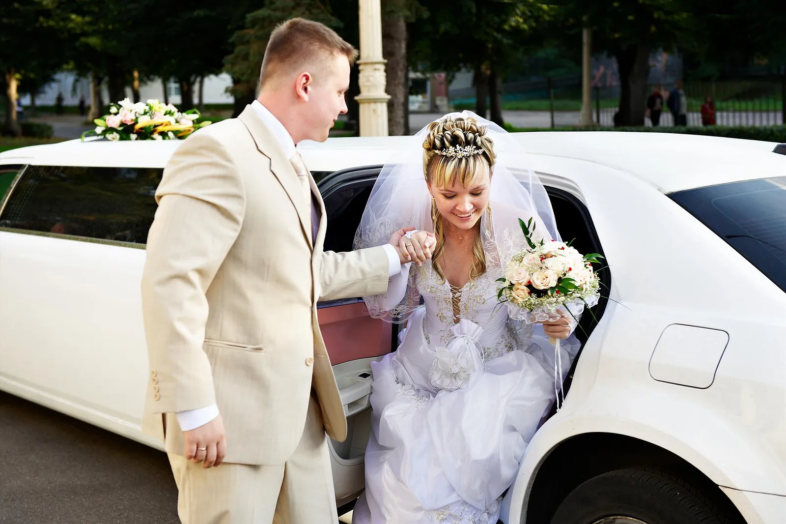 A bride and groom beside a white limousine