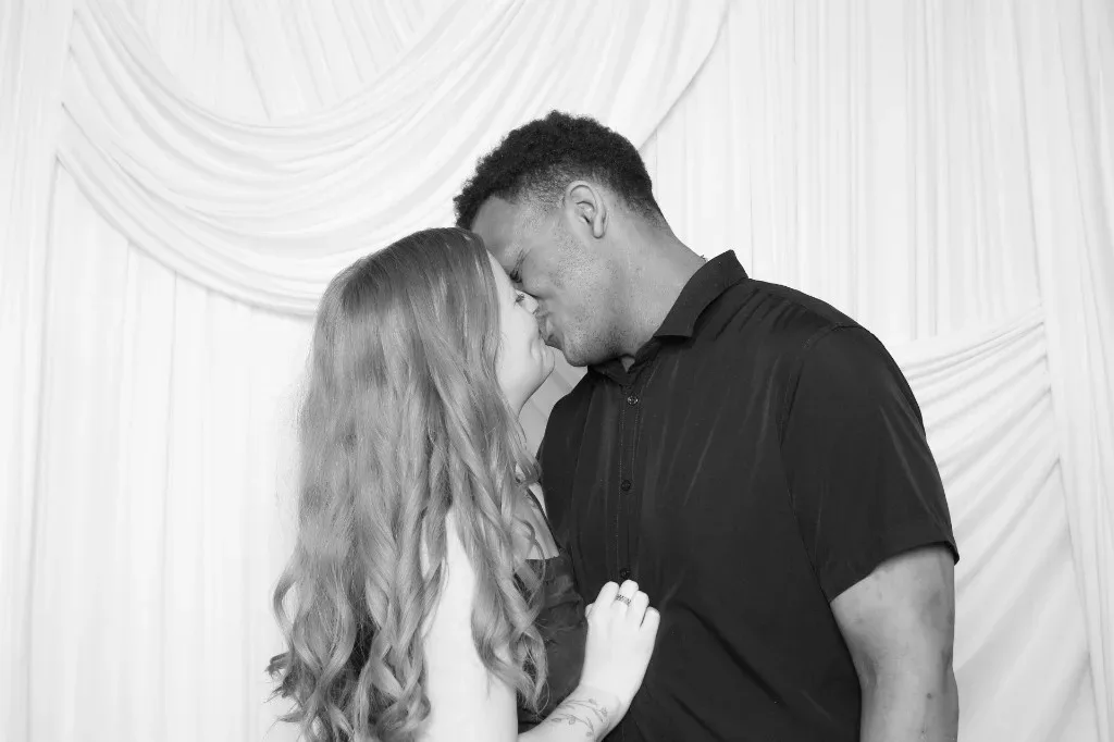A black-and-white photo booth kiss
