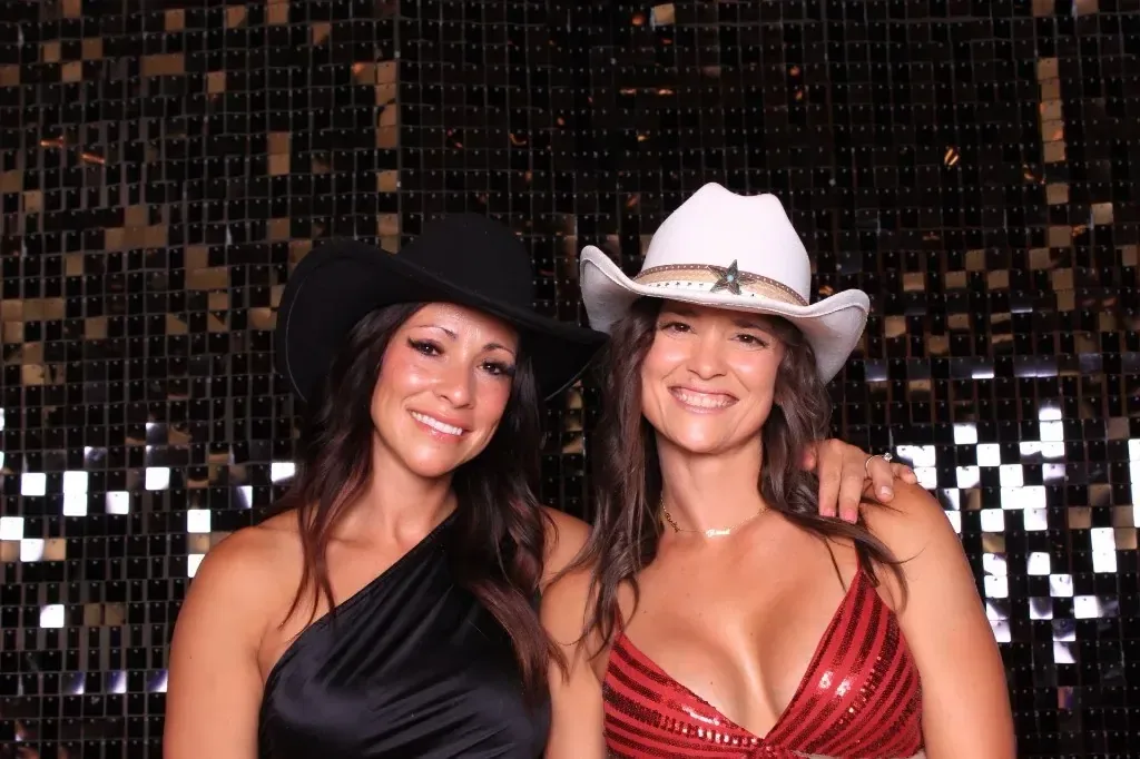 Two guests in cowboy hats in front of a gold shimmer wall