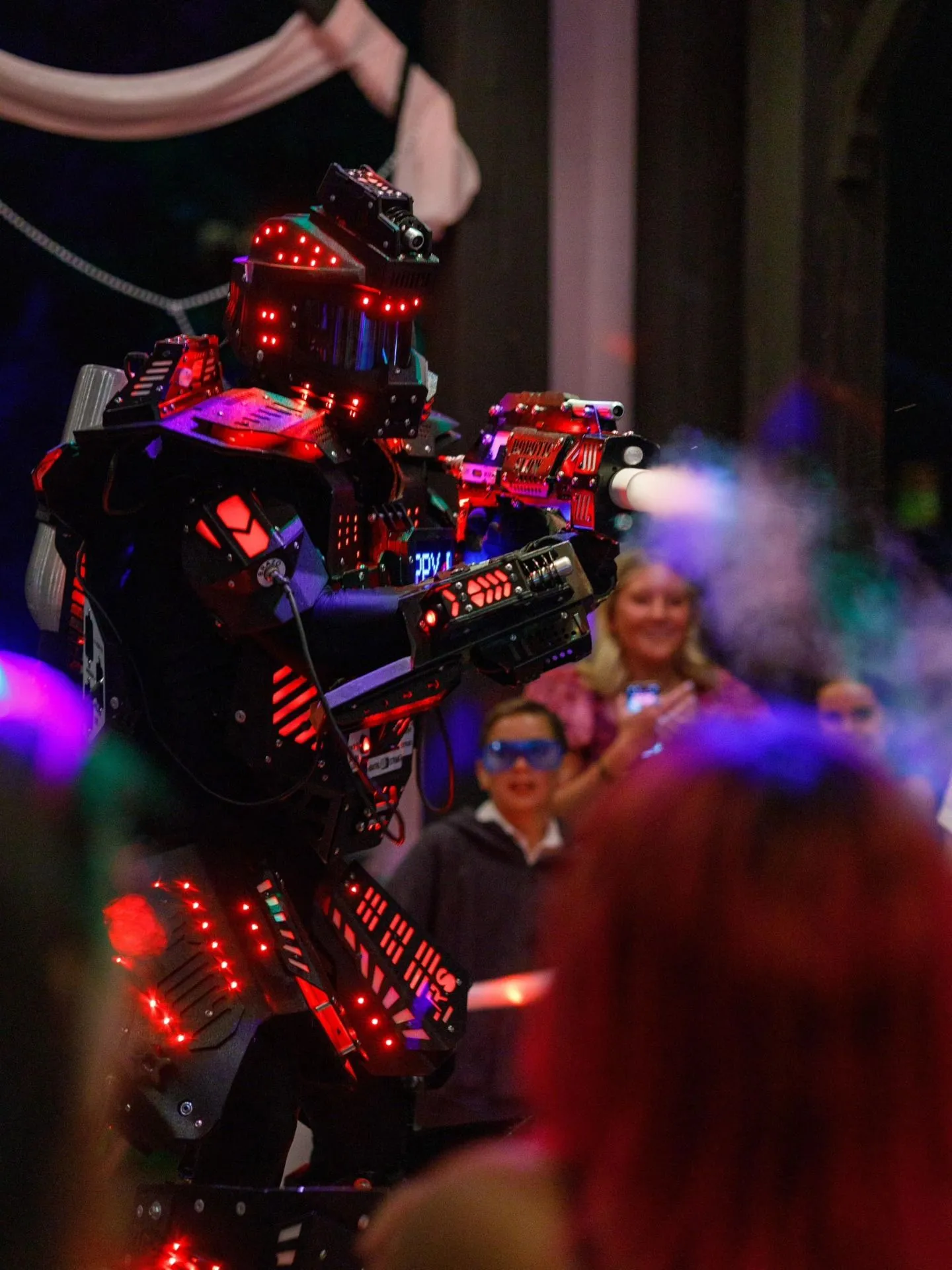 A red LED robot firing a CO₂ cannon over the crowd