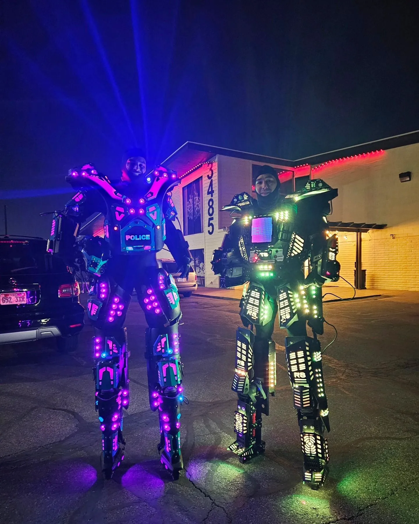 Two Robotic Show performers in glowing LED robot suits at night