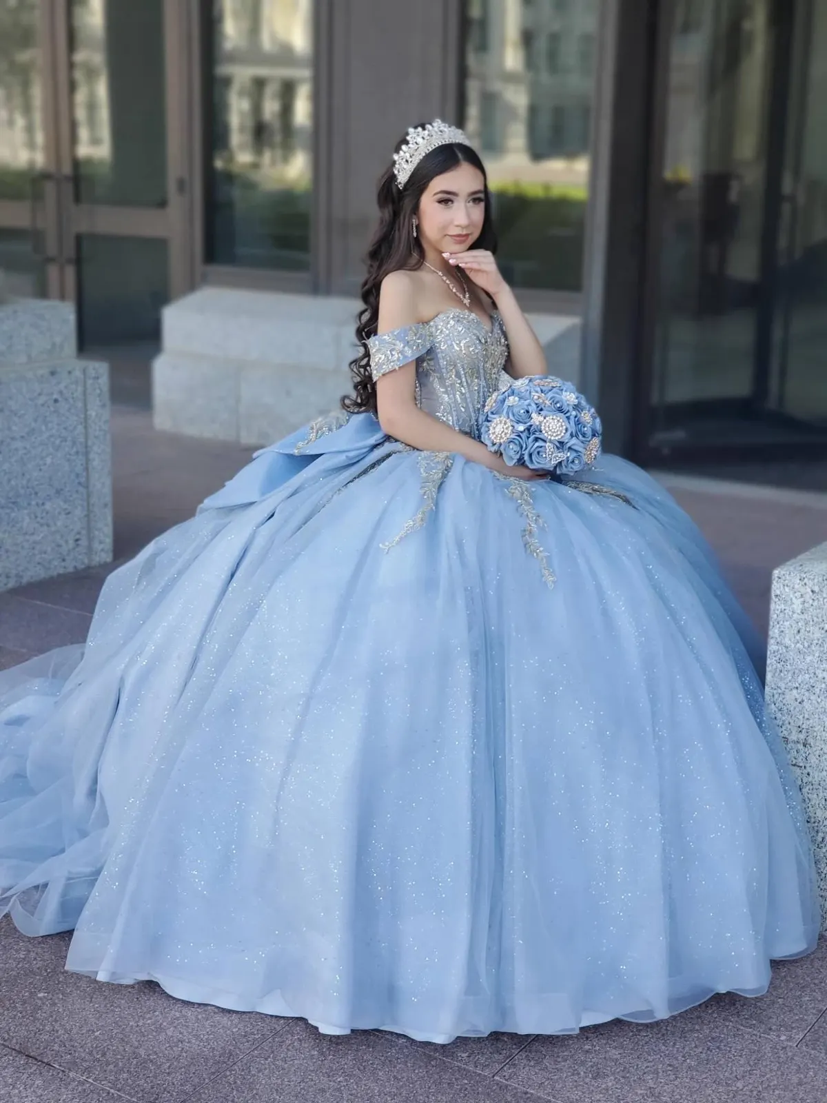 Quinceañera in a sky blue gown holding a matching bouquet