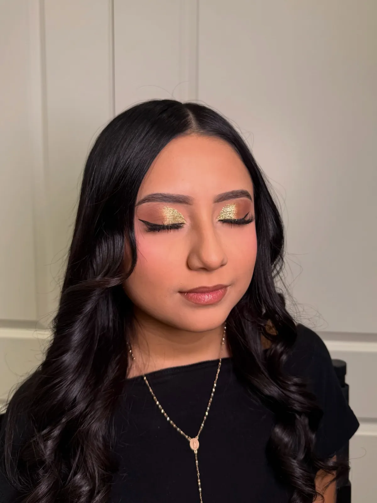 A gold glitter eye look with a winged liner